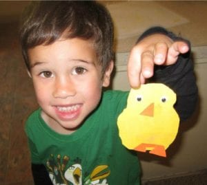 preschool boy holding a duckling he made at art
